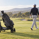 Illustration générée par IA : un chariot de golf suiveur accompagne un joueur sur le parcours.